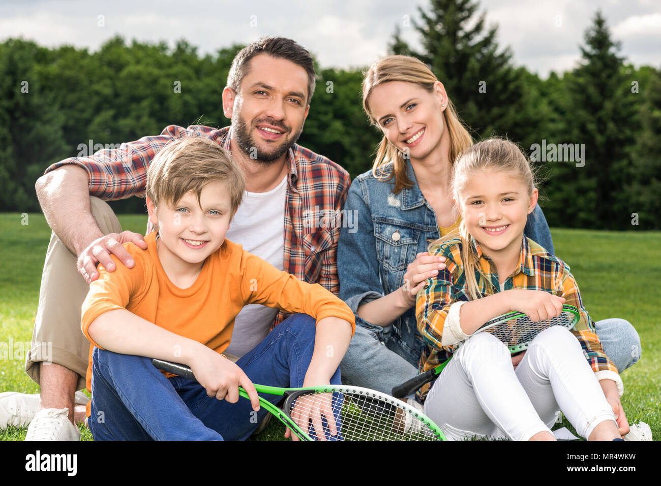 La famiglia felice con due figli azienda badminton racchette e sorridente in telecamera Foto Stock