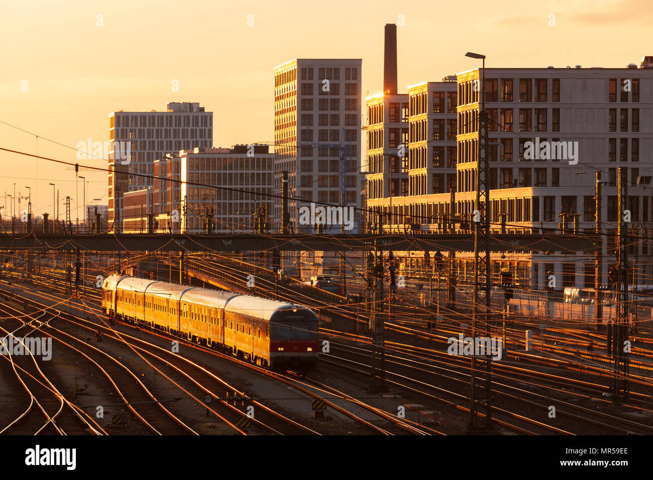Monaco di Baviera / Germania: Via Campo della stazione principale di Monaco con edifici moderni in background e un treno in primo piano Foto Stock