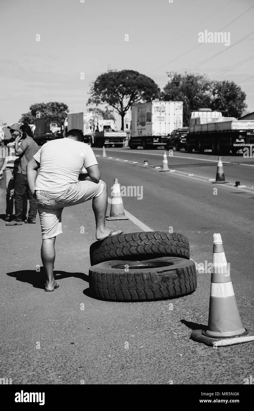 Campo Grande, Brasile - 24 Maggio 2018: l uomo in gamba di appoggio sui pneumatici dei camion a terra per la sosta di autocarri sulle strade del Brasile per protestare o Foto Stock