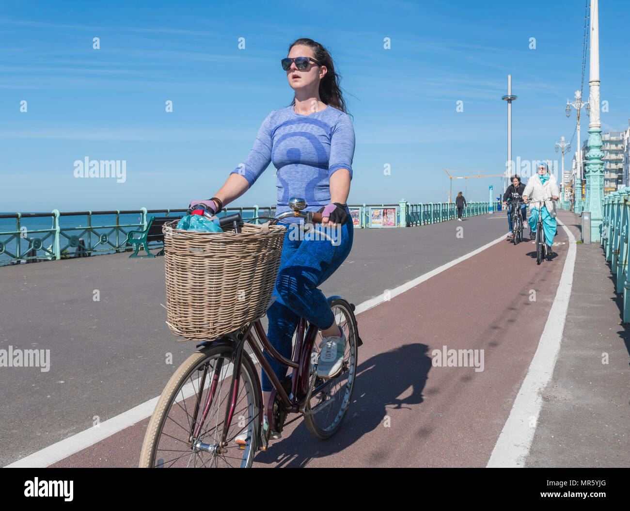 Una donna in bicicletta su un percorso di ciclo con un carrello, seduto in posizione eretta con una buona postura su una pista ciclabile in Brighton, East Sussex, Inghilterra, Regno Unito. Foto Stock