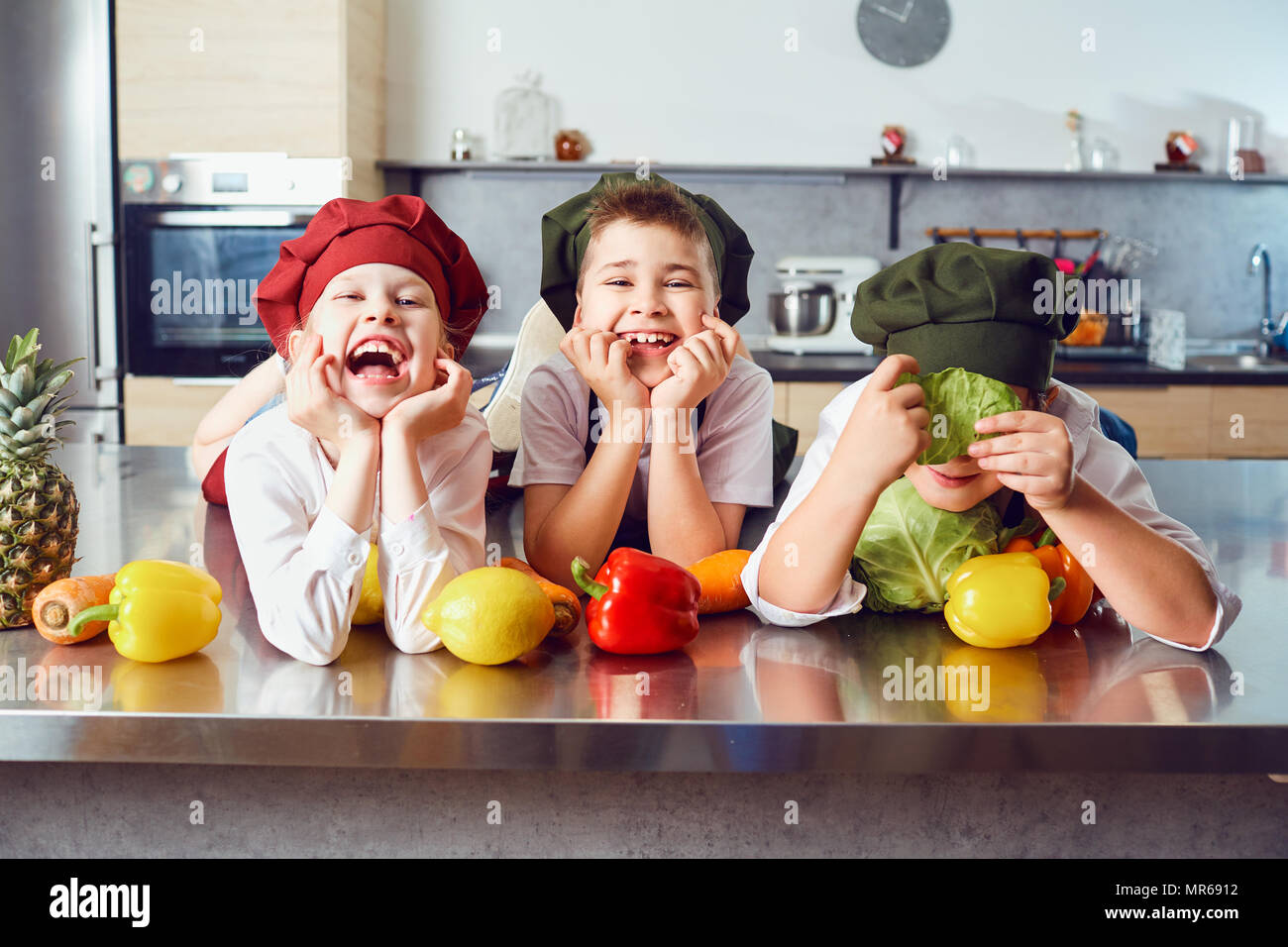 Bambini divertenti nell'uniforme di cuochi in cucina. Foto Stock