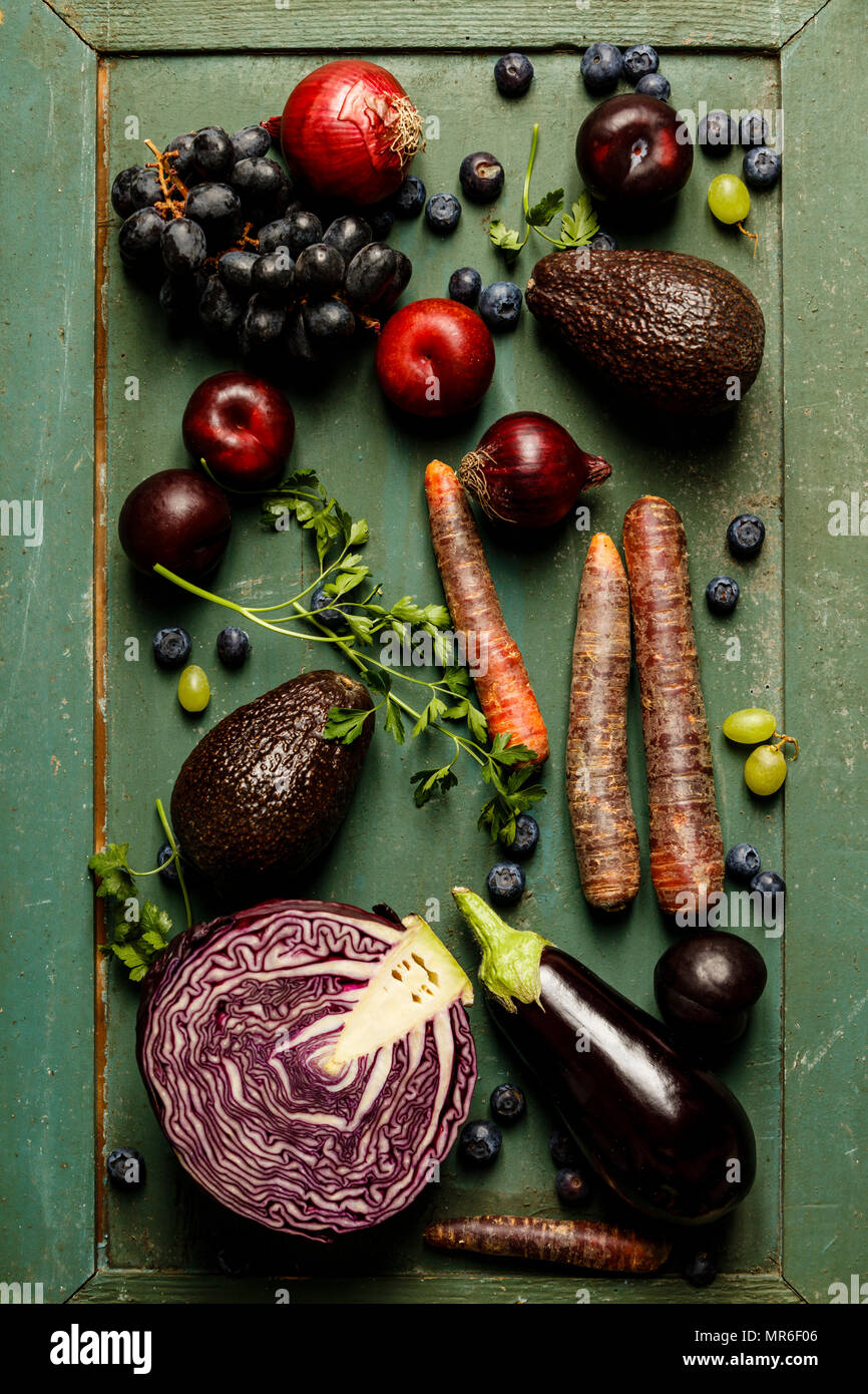 Assortimento di materie organiche viola di ingredienti: Melanzane, cipolle, bacche, carote, uva, cavolo, avocado, prugne su sfondo rustico. Vista superiore, g Foto Stock