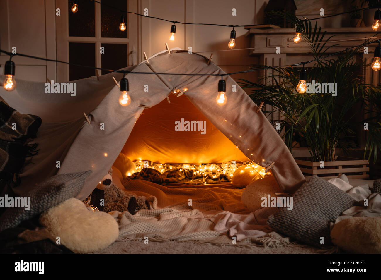 Tenda a mano con coperte, cuscini, giocattoli e luci in camera Foto Stock