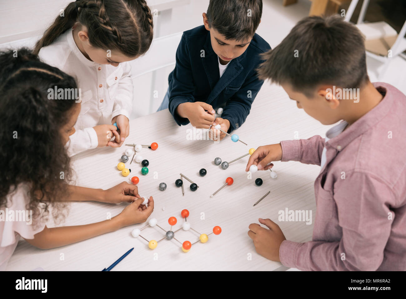 Concentrato schoolkids multietnica studiando con modello molecolare a lezione di Chimica Foto Stock