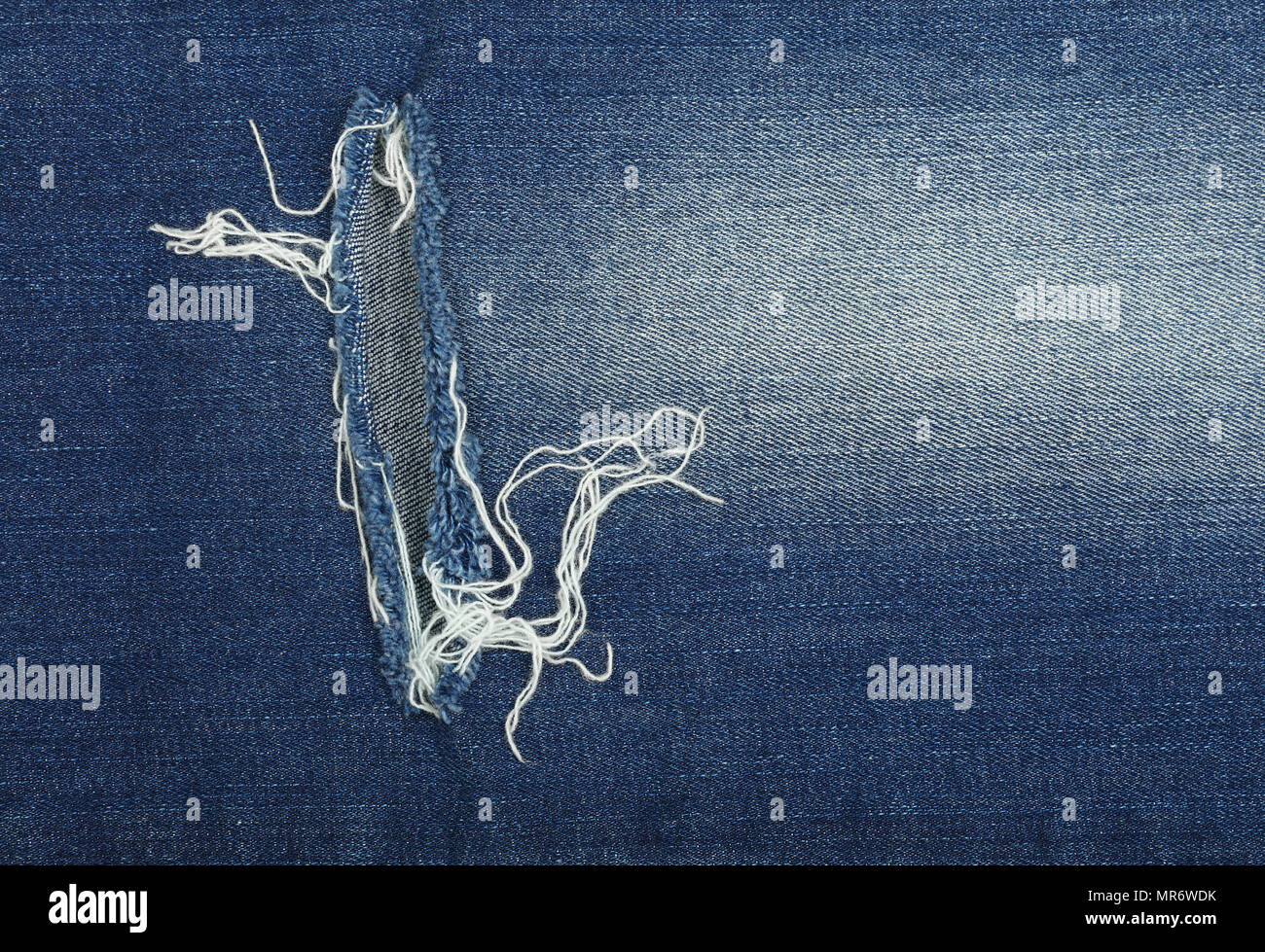 Dark indigo blue Cotone lavato jeans denim sfondo texture con foro e filettature, close up Foto Stock