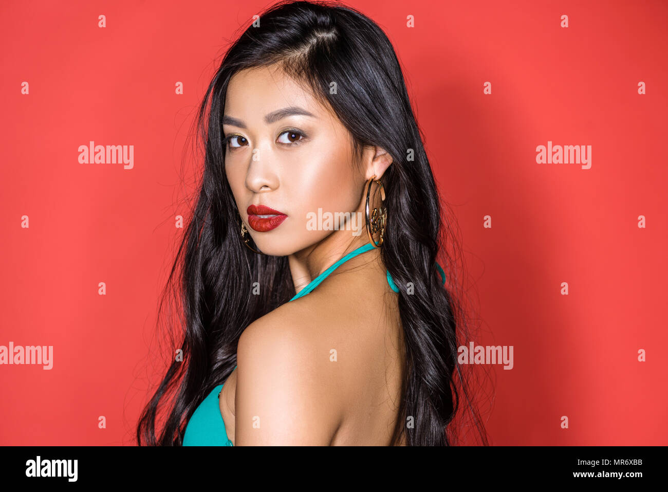 Ritratto di una bella donna asiatica in costume da bagno color turchese in piedi mezza girata e guardando la fotocamera Foto Stock