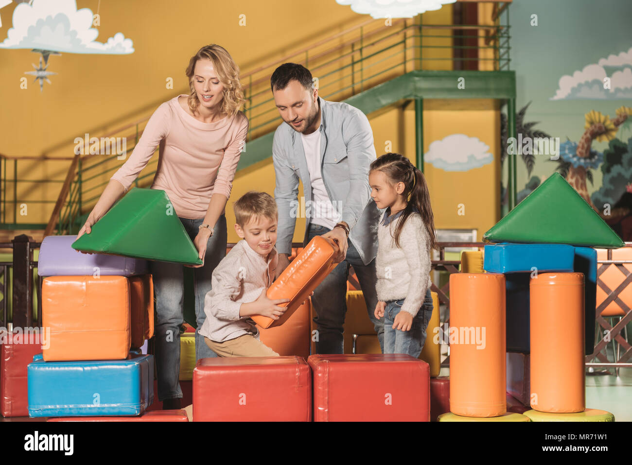 La famiglia felice insieme giocando con i blocchi colorati in piscina il centro del gioco Foto Stock