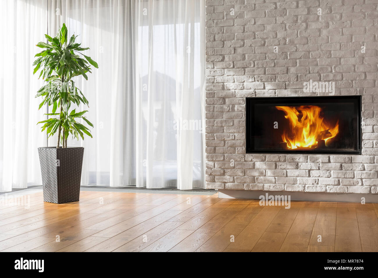 Luminoso soggiorno con caminetto, muro di mattoni e una pianta ornamentale  Foto stock - Alamy