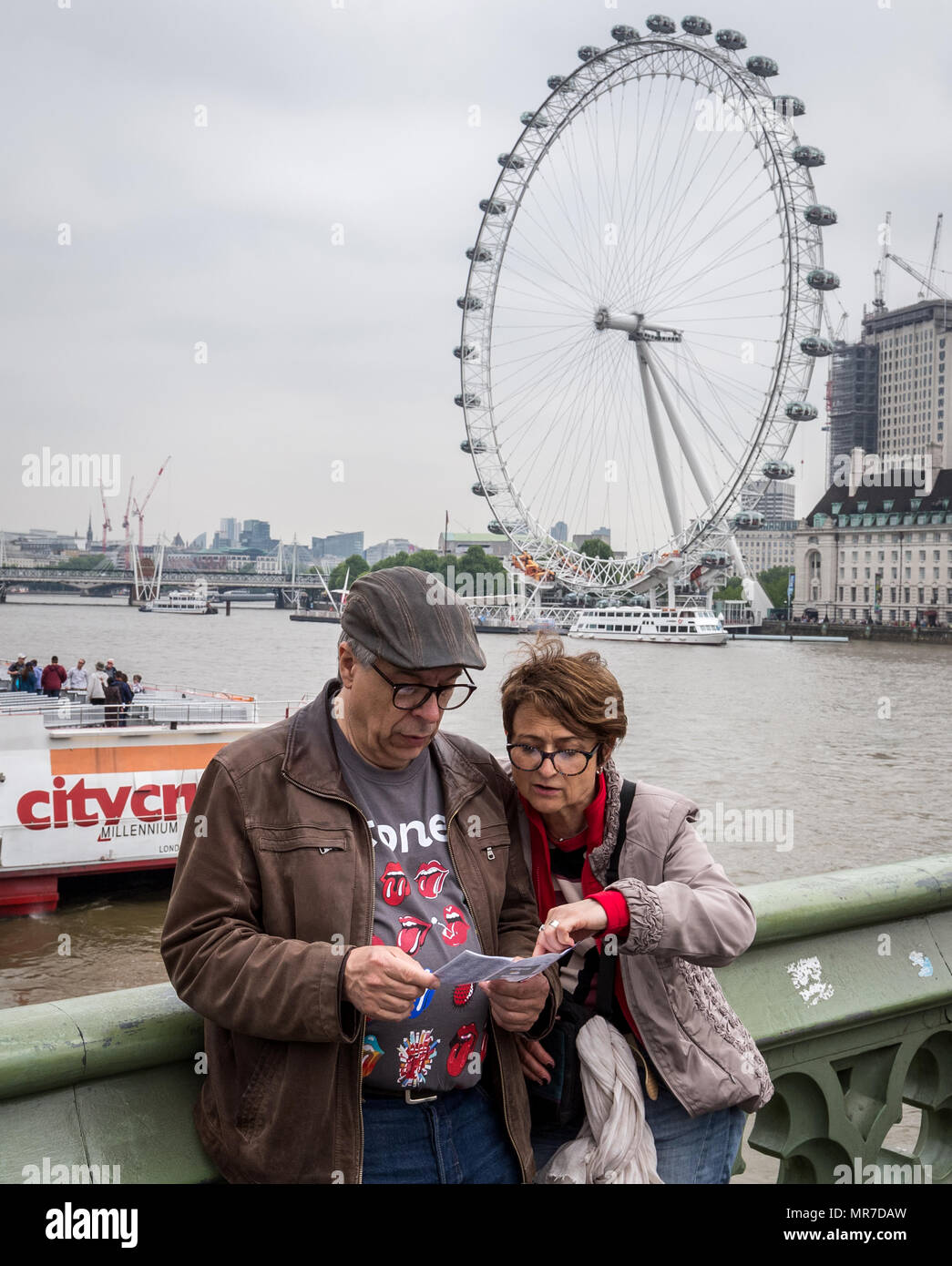 I turisti verificare la loro mappa durante un pomeriggio nuvoloso sul Westminster Bridge con il London Eye in background. Londra, Regno Unito. Foto Stock I turisti verificare la loro mappa durante un pomeriggio nuvoloso sul Westminster Bridge con il London Eye in background. Londra, Regno Unito. Foto Stock