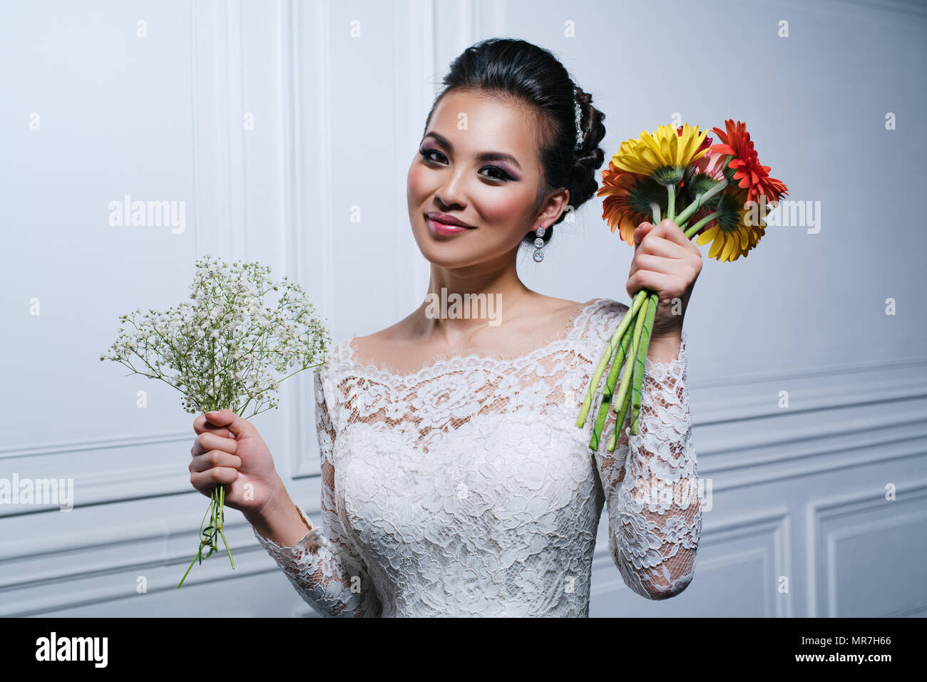Sorridente giovane donna asiatica in abito bianco con fiori ritratto di moda Foto Stock