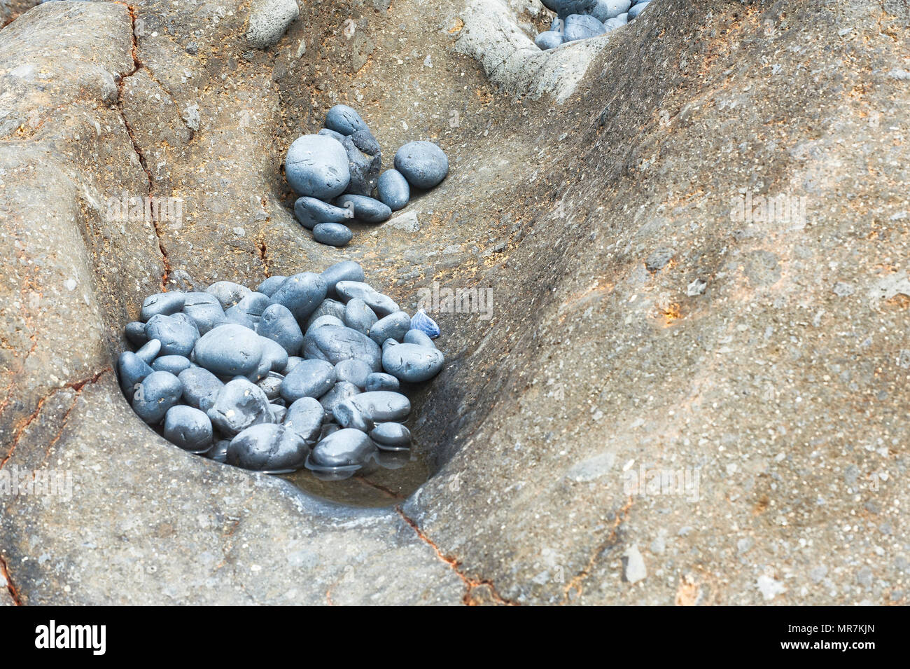 Primo piano della cavità naturale nella caratteristica geologica riempiti con ciottoli alla spiaggia di ciottoli a Yaquina capo del Parco Statale di Newport Oregon Foto Stock