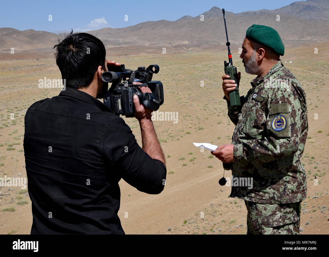 Un locale reporter afgano pellicole come Afghan Air Force Stati comunica sul terreno con una A-29 Super Tucano pilota su comunicazioni radio vicino a provincia di Logar, Afghanistan, 21 maggio 2017. Treno, consulenza, assistenza Command-Air (TAAC-aria) consulenti, terrà un live-formazione antincendio esercizio per una classe di afgane Tactical Air coordinatori. Prima dell'esercizio, i consulenti da TAAC-aria effettuato tre settimane di formazione in aula come parte di aria-terra di integrazione. Il live fire esercizio è parte di una valutazione pratica prima di Afghan Air Force Il personale può laurearsi come ATACs. (U.S. Air Force foto da Foto Stock