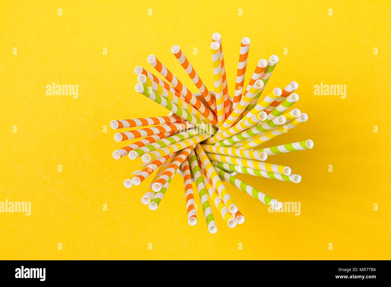 In un bicchiere di carta sono colorati cocktail tubi su sfondo giallo Foto Stock