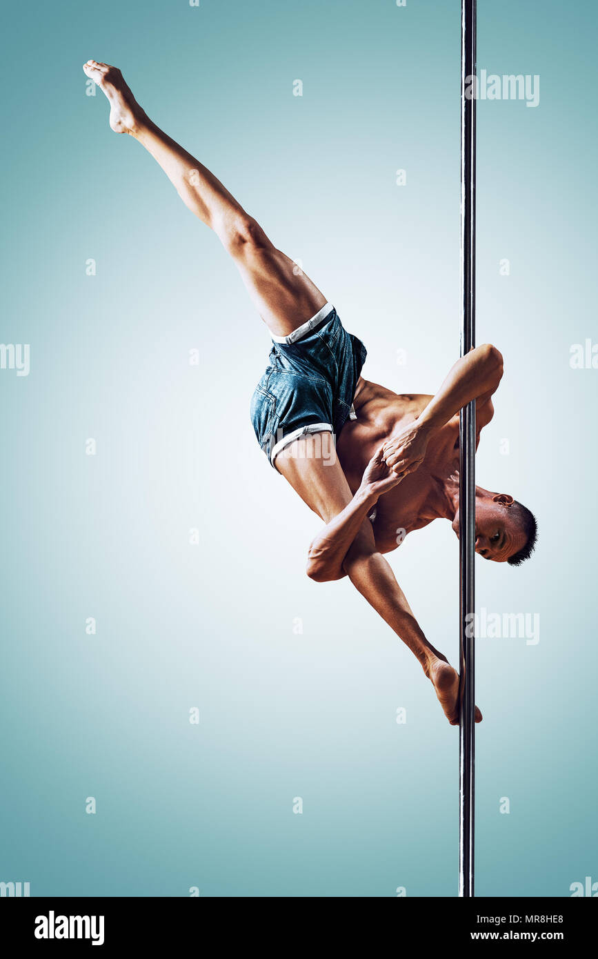Giovane uomo forte pole dancing su blu e sfondo bianco Foto Stock