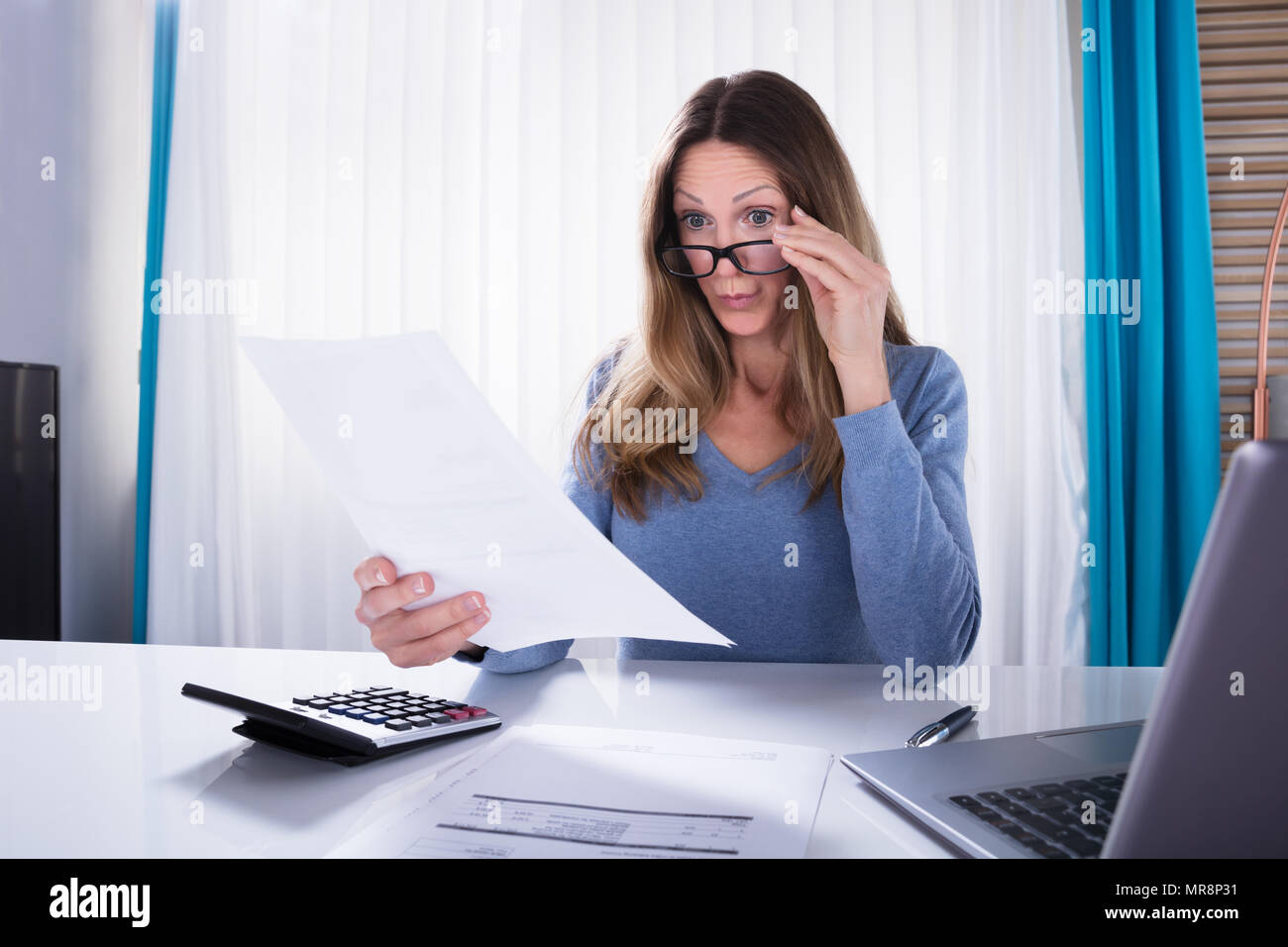 Close-up di matura scioccato Donna che guarda il documento al lavoro Foto Stock