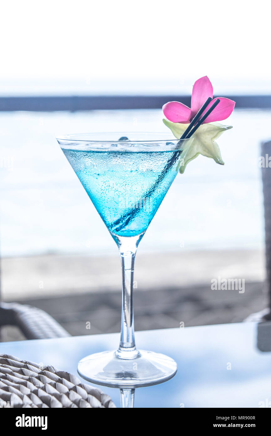 Blue il cocktail in una coppetta Martini con fiore rosa guarnire e star fruit, più cannucce di plastica, a Apia, Isola Upolu, Samoa Occidentale e Sud Pacifico Foto Stock