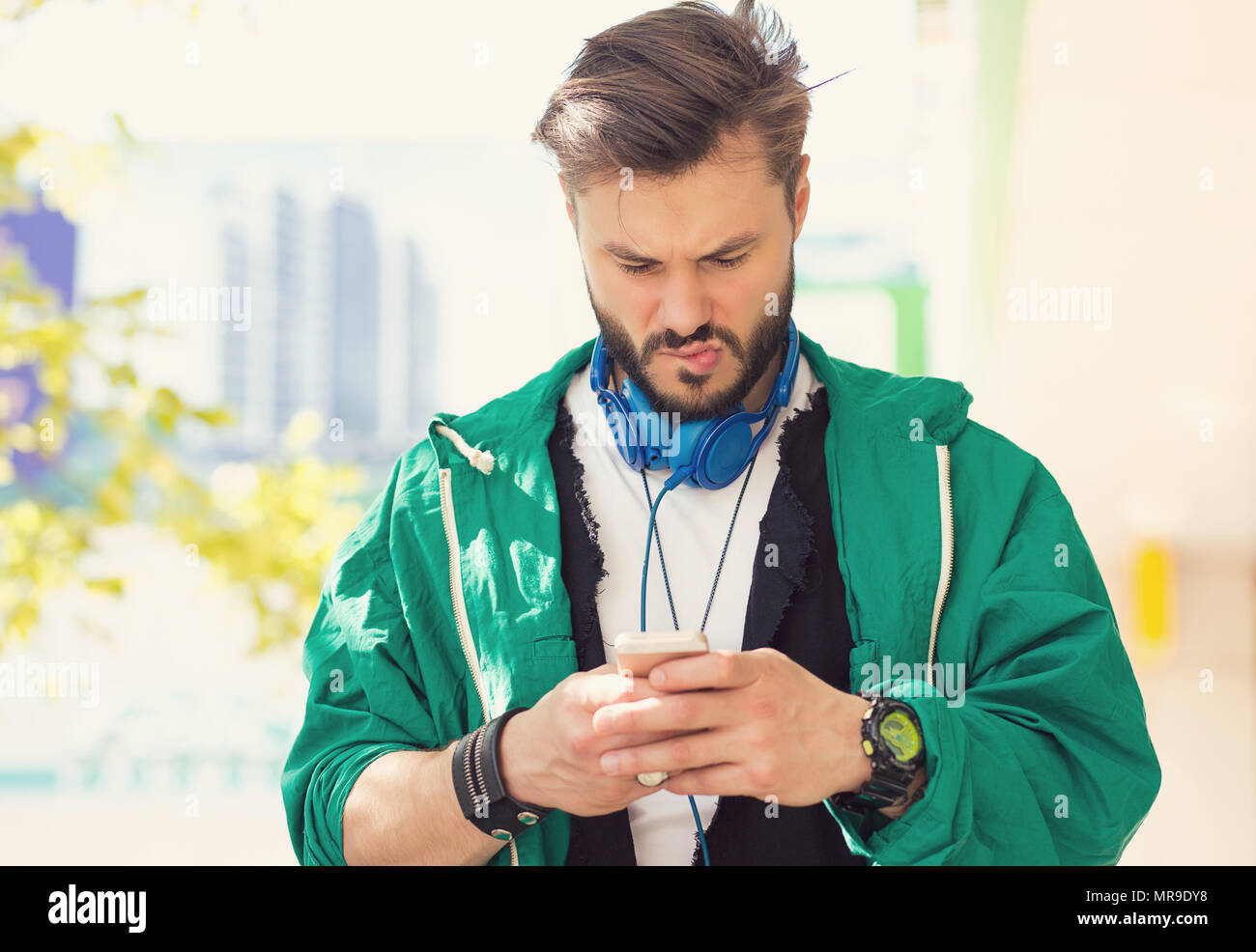 Ritratto di un grave confuso uomo parlando gli sms sul cellulare orinato con conversazione sul paesaggio urbano all'aperto sullo sfondo. Negativo emotio umana Foto Stock