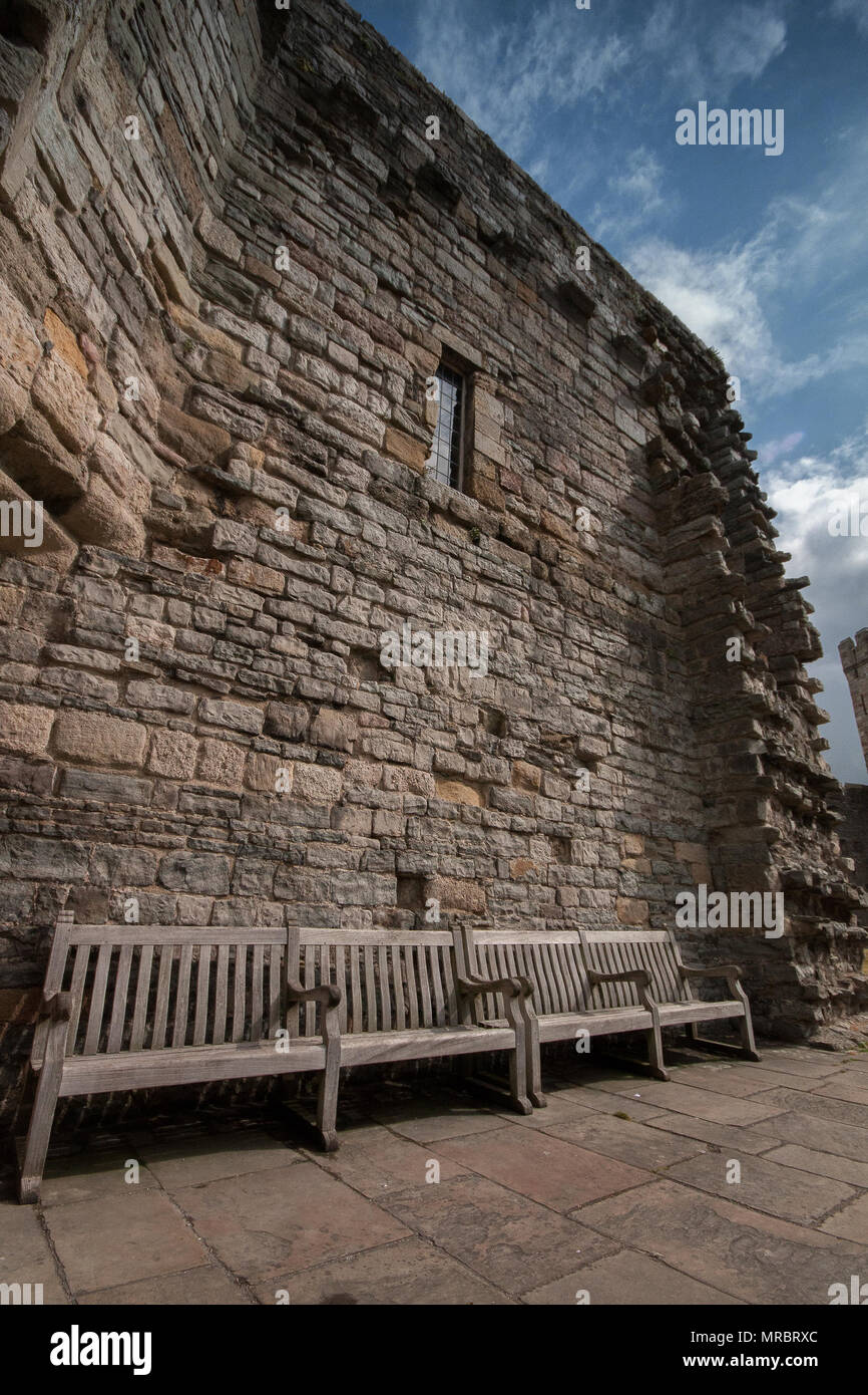 Panche da un muro di pietra all'interno di Caernarfon Castle nel Galles del Nord, Regno Unito. Foto Stock