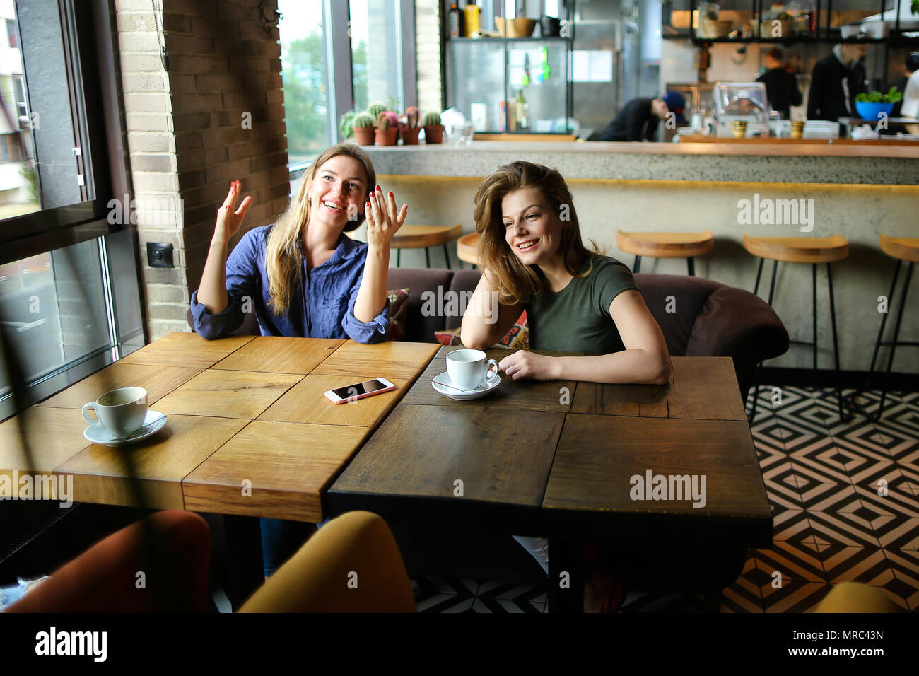 Positive le donne sedute presso il cafe con tazze di caffè e sorridente. Foto Stock