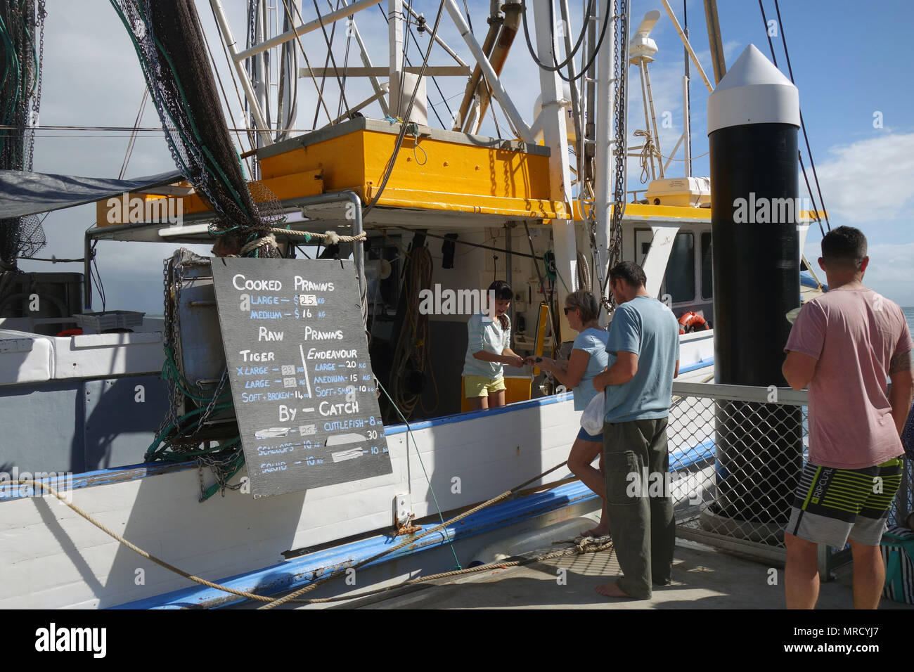 Persone che acquistano i gamberetti dal trawler a wharf, Port Douglas, Queensland, Australia. No signor o PR Foto Stock