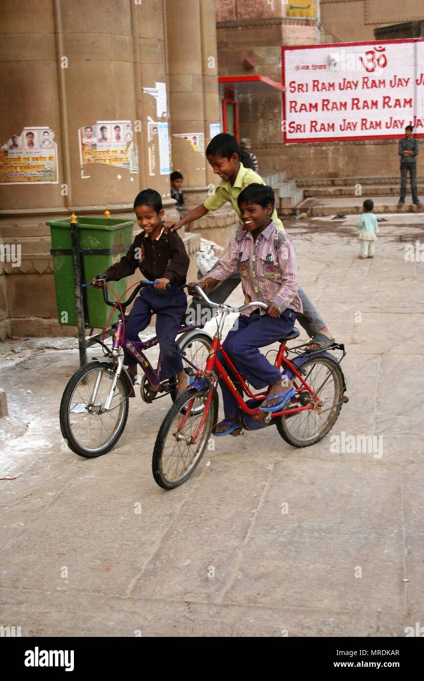 Due bambini indiani in biciclette con un bilanciamento in Medio, Varanasi, India Foto Stock