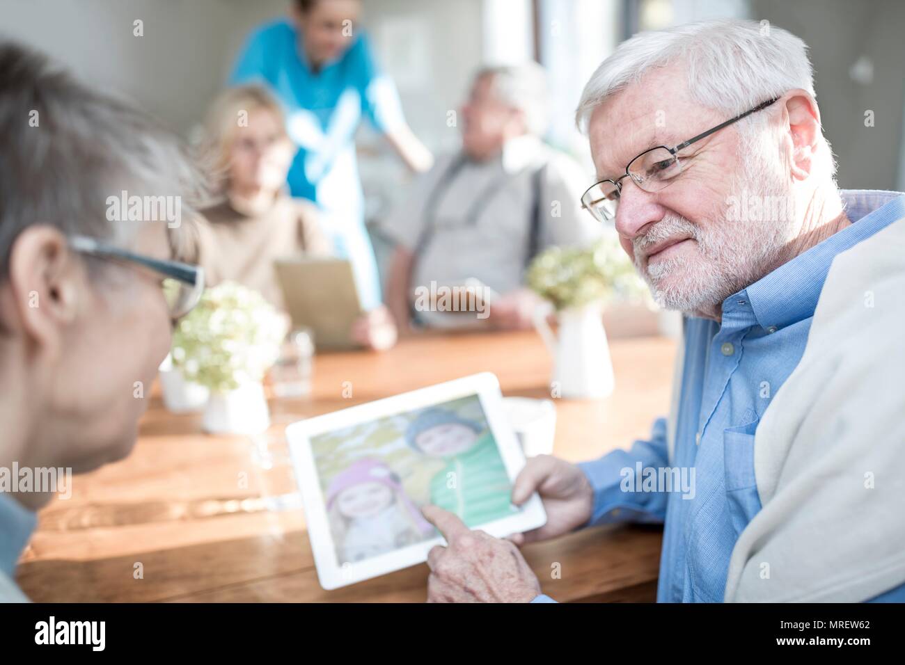Senior adulti guardando le foto sulla tavoletta digitale in casa di cura. Foto Stock