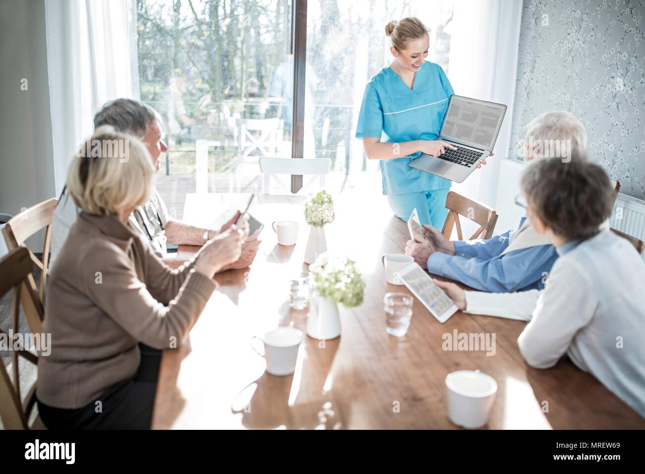 Lavoratore di cura che mostra senior adulti portatile nella casa di cura. Foto Stock