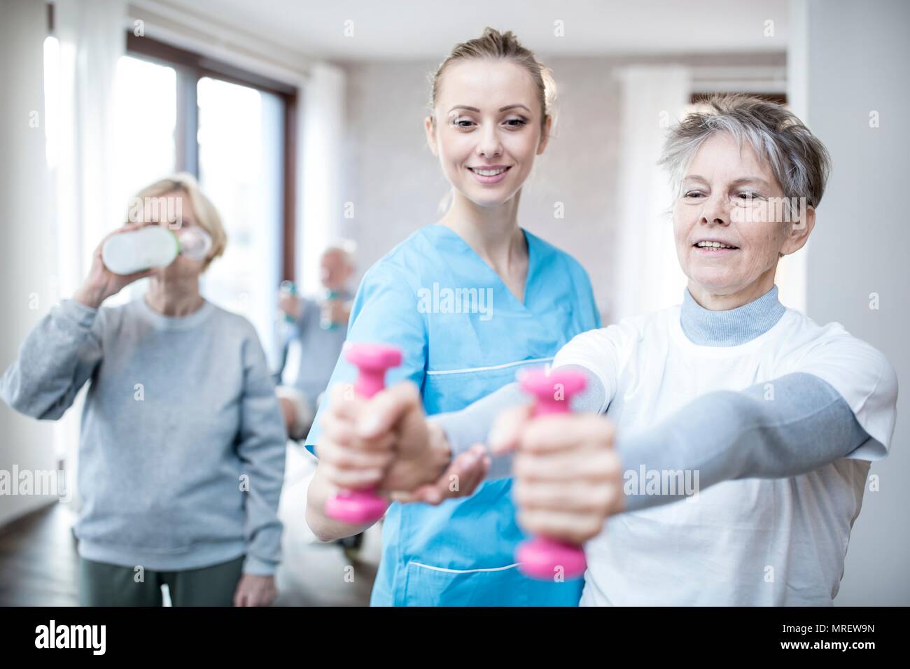 Donna senior di contenimento dei pesi a mano, fisioterapista aiutando. Foto Stock