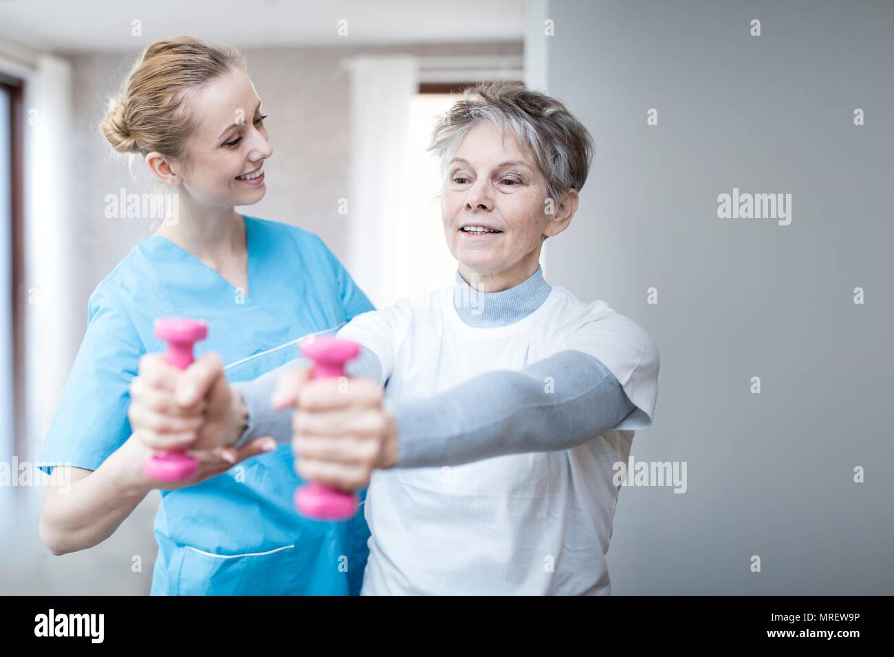 Donna senior di contenimento dei pesi a mano, fisioterapista aiutando. Foto Stock