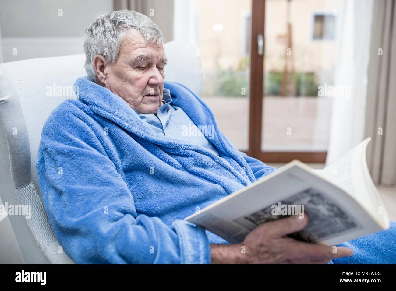 Senior uomo rivista di lettura nella casa di cura. Foto Stock