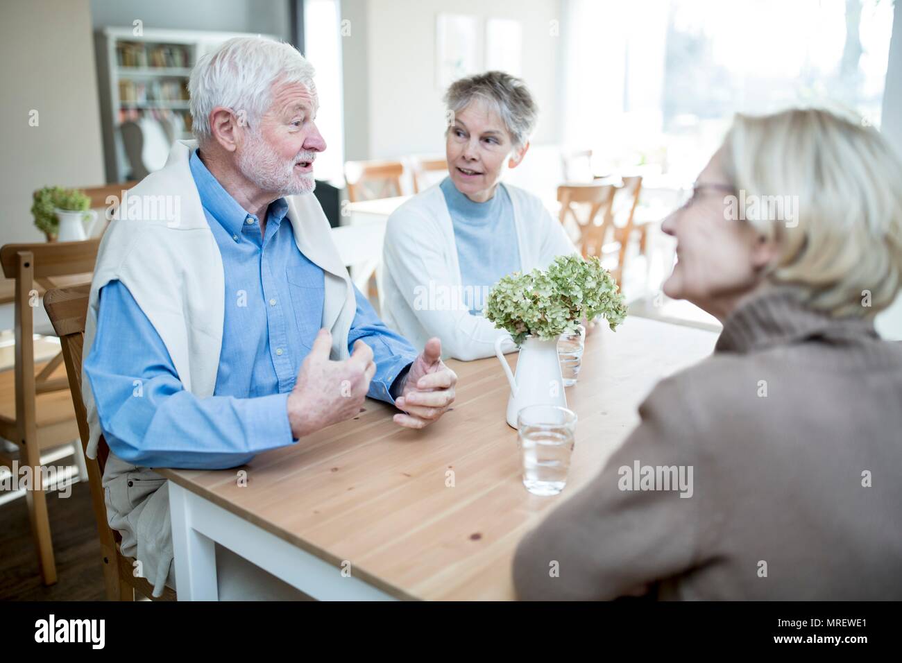 Senior uomo che parla di due amici di sesso femminile nella casa di cura. Foto Stock