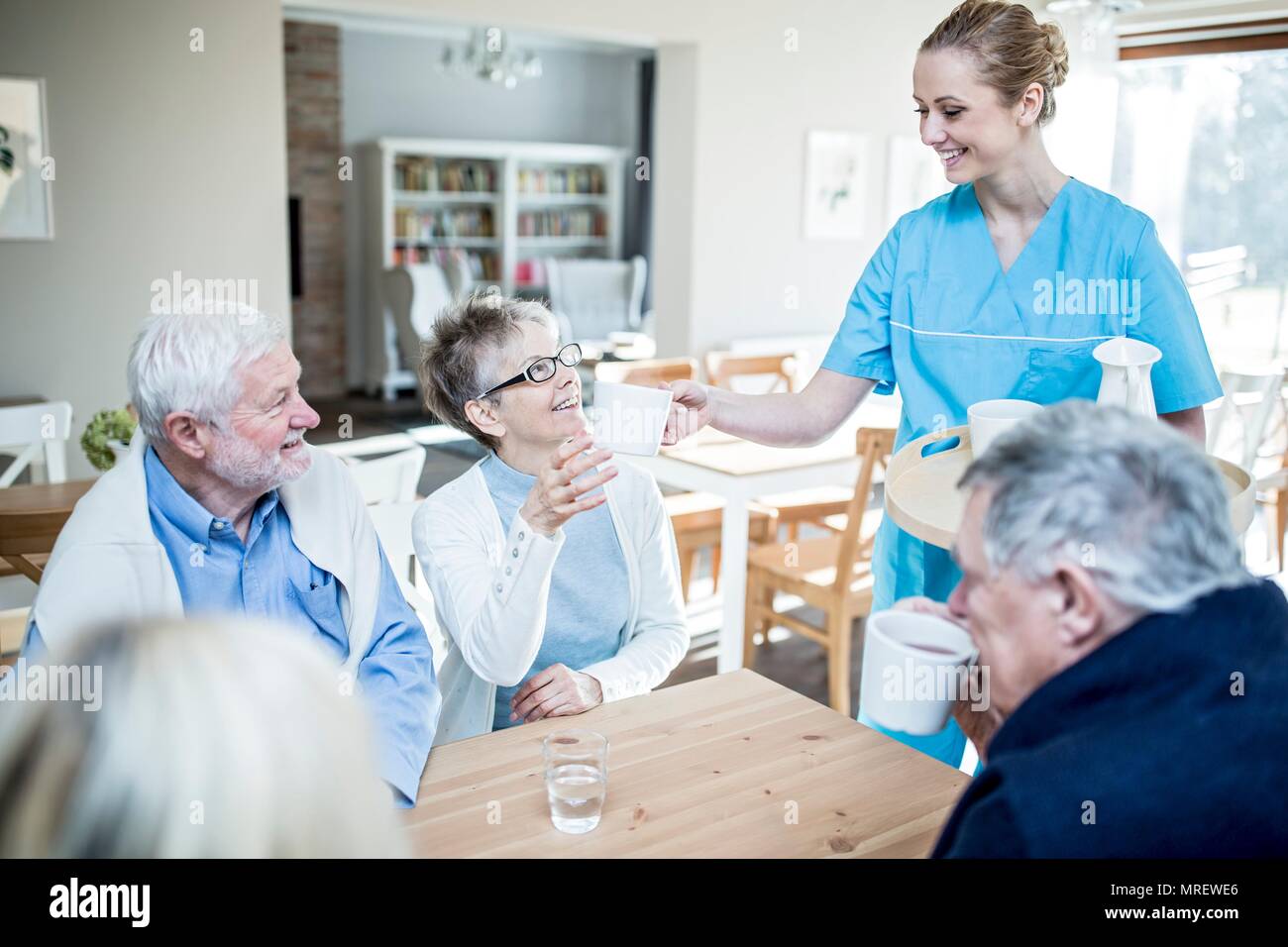 Lavoratore di cura che serve tè al senior donna nella casa di cura. Foto Stock