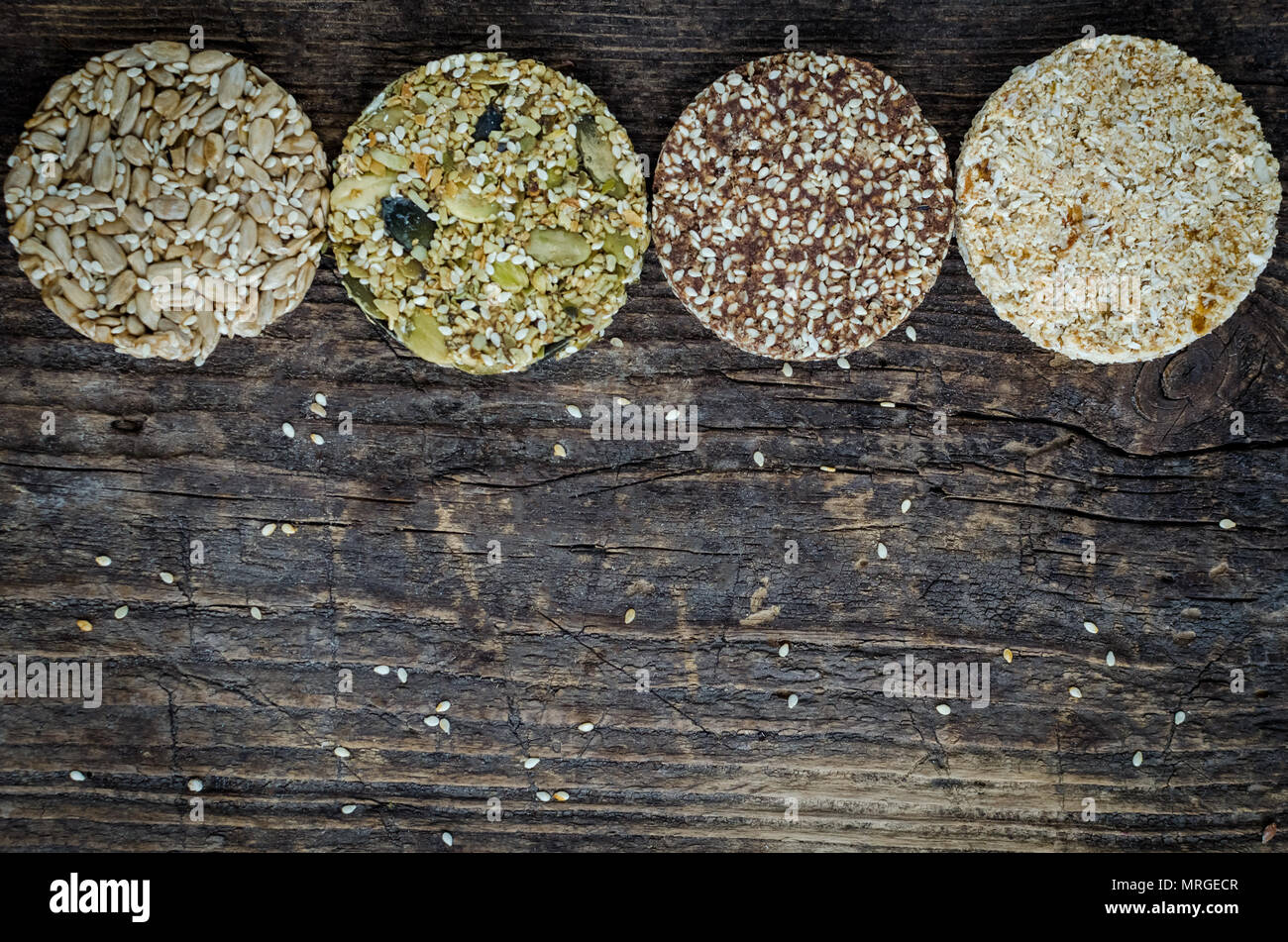 Dessert snack di cereali. Fitness alimenti dietetici. Kozinaki con sesamo, arachidi, semi di girasole e semi di zucca, date sul vecchio rustico di legno. Vegan healt Foto Stock