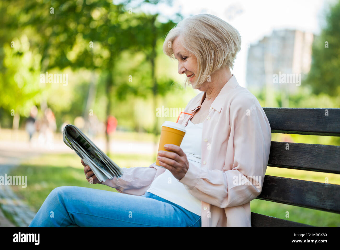 Adulto donna seduta in posizione di parcheggio e la lettura dei quotidiani. Foto Stock