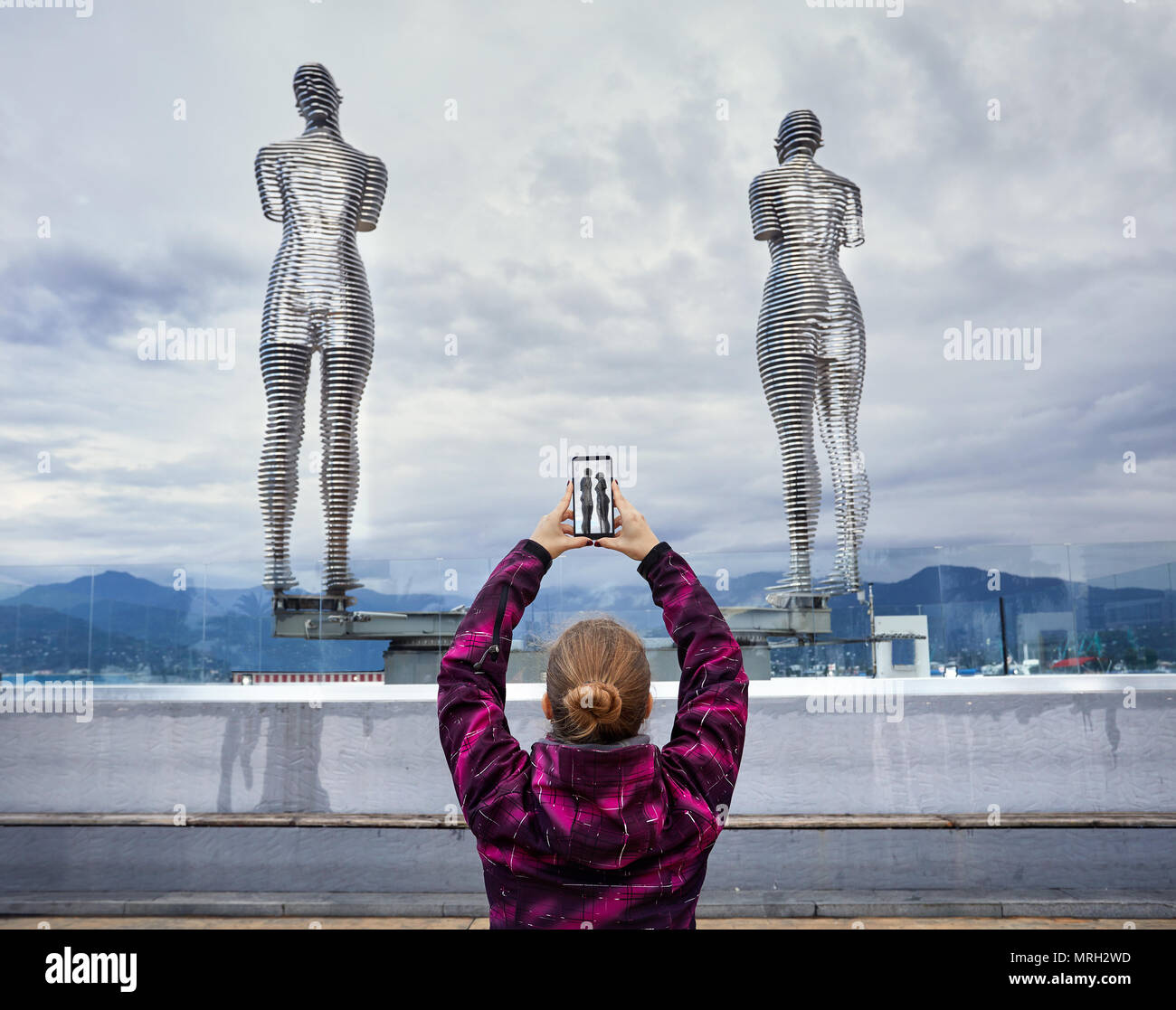 Donna turistica foto di incollamento di statue Ali e Nino con lo smartphone a Batumi, Georgia Foto Stock