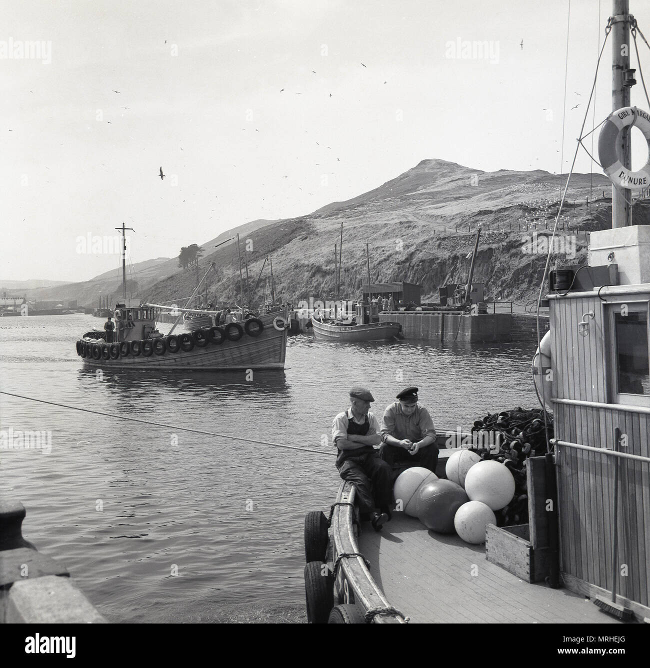 Degli anni Cinquanta, foto storiche di una piccola barca da pesca o drifter entrando in un mare di apertura o di ingresso in prossimità della cittadina di mare di Whitby, North Yorkshire, Inghilterra, Regno Unito. Il paese era noto in questa epoca per la pesca delle aringhe e i pescatori utilizzate reti da posta derivanti come visto sulla barca in primo piano. Foto Stock