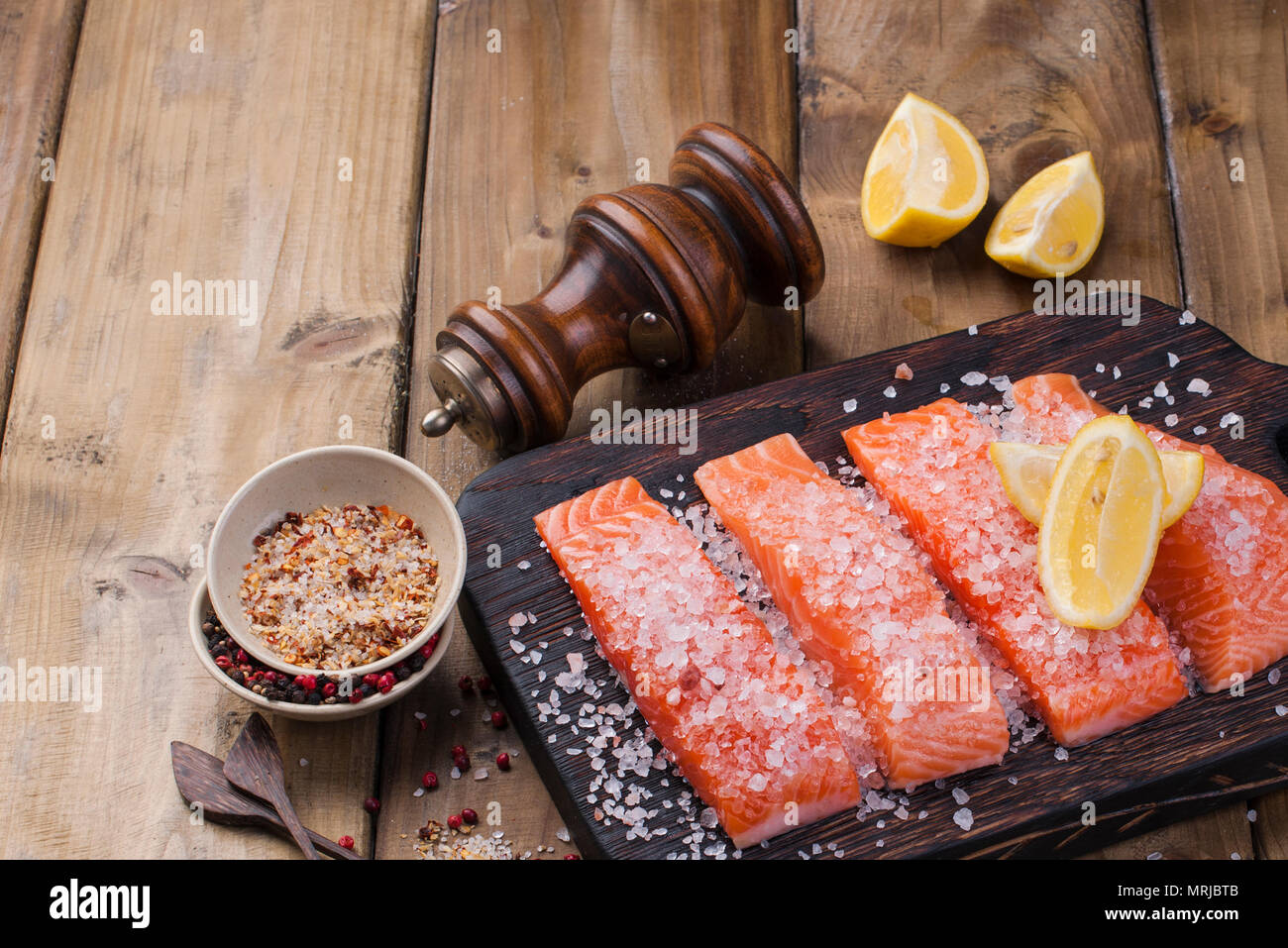 Materie filetto di salmone con pepe di animelle e sale sulla carta da forno tema rustico con copy-spazio. Foto Stock