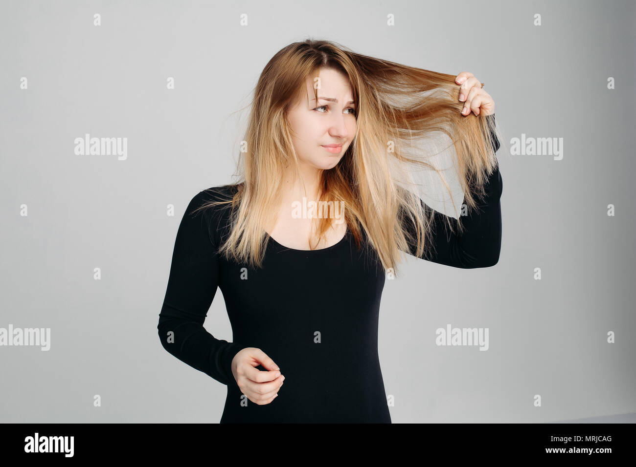 Pretty Woman holding disordinati capelli in una mano e la spazzola per capelli in un'altra. Foto Stock
