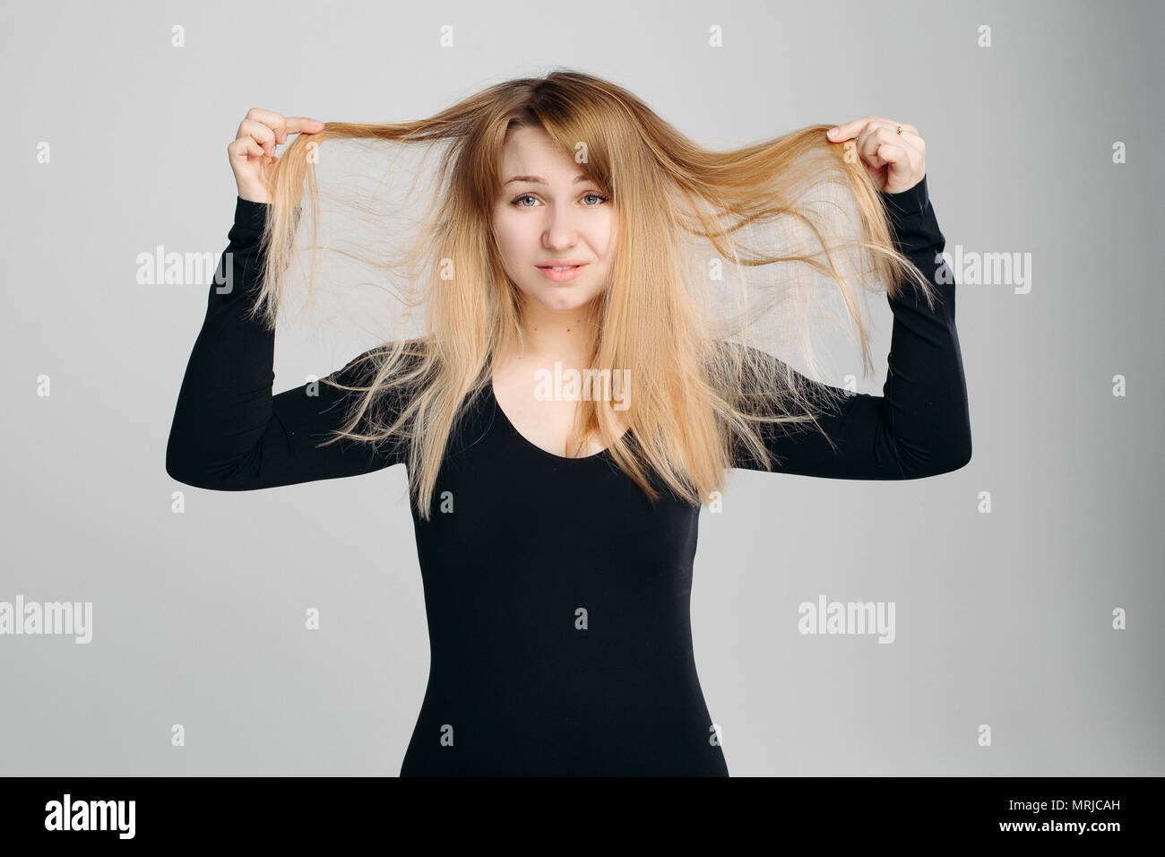 Pretty Woman holding disordinati capelli in mano. Foto Stock