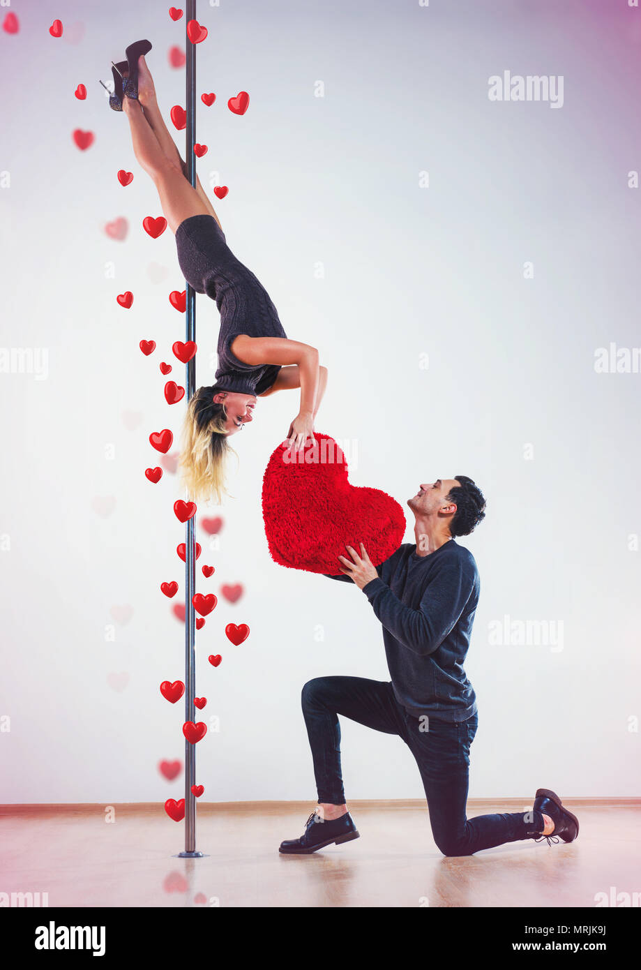 Giovane uomo e donna pole ballerini. L'uomo ha espresso sentimenti e dando grande cuore rosso. Il concetto di amore. Foto Stock