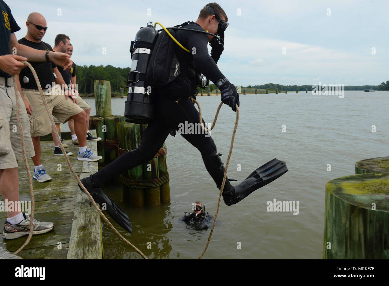 Stati Uniti Pfc dell'esercito. Kyle Grimes, ingegnere 74Dive distacco, 92Battaglione tecnico di seconda classe subacqueo, salti in James River per ispezionare la terza porta di piloni durante una missione di immersioni a base comune Langley-Eustis, Va., 20 giugno 2017. Per impedire la massiccia alla realizzazione di progetti di ricostruzione che si verifichi in futuro, i subacquei guardare attentamente per individuare eventuali danni o irregolarità sono in grado di fissare facilmente mentre si ispezionano i piloni. (U.S. Air Force foto/Airman 1. Classe Kaylee Dubois) Foto Stock