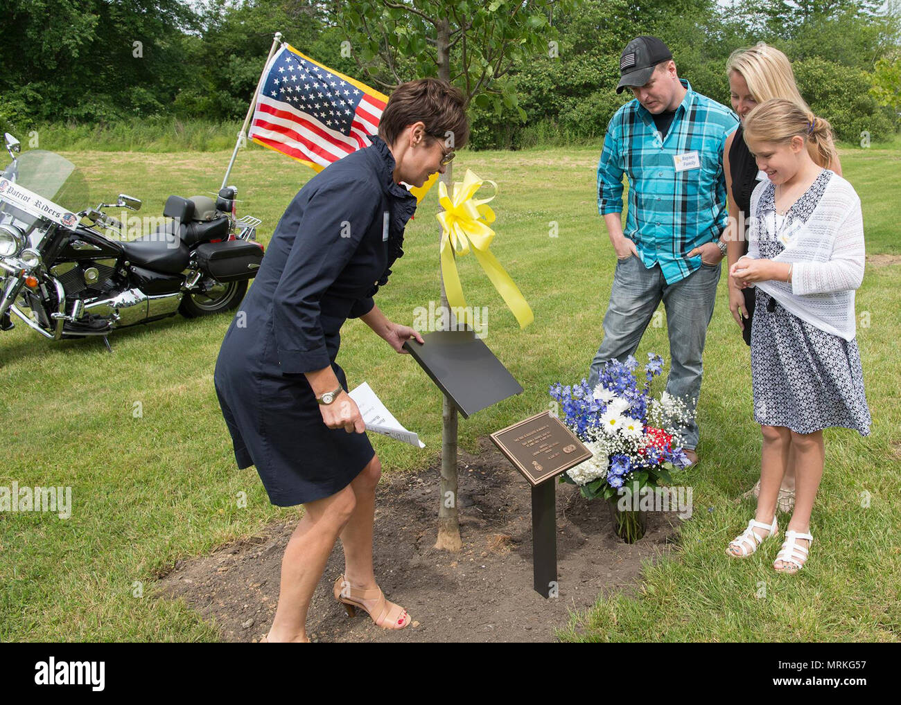 Shelly Raynes svela una placca nella parte anteriore di un albero dedicato al defunto marito, pensionato Tech. Sgt. A John una Raynes, durante un parco memoriale Inaugurazione a Hanscom Air Force Base, Massachusetts, 16 giugno, mentre Giovanni Jr., Ashley e Hannah grazia a guardare. Raynes ha lavorato per le forze di sicurezza, Affari pubblici e ingegneria civile durante la sua permanenza alla Hanscom. Onorato anche durante la manifestazione è stata Dana E. Kirane e Dennis "Dennie" Guthrie. (U.S. Air Force foto di Jerry Saslav) Foto Stock