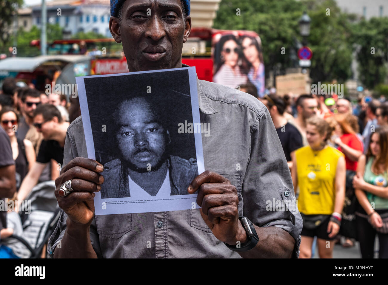 Barcellona, Spagna. 27 Maggio, 2018. Un uomo nero mostra il ritratto di una persona che muore a causa delle legislazioni in materia di immigrazione. Più di 3 mila persone hanno dimostrato nel centro di Barcellona a sostegno delle persone che volontariamente prendere 37 giorni bloccato in La Massana school di Barcellona per chiedere la cittadinanza spagnola senza la necessità di passare qualsiasi test di livello sulla cultura spagnola e la lingua. La protesta si estende anche la petizione per rovesciare il diritto di immigrazione e che regola gli arresti e le espulsioni. Credito: SOPA Immagini limitata/Alamy Live News Foto Stock