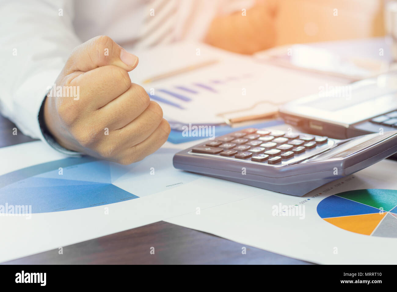 Squeeze di imprenditore con il grafico della carta e delle finanze oggetto ufficiale su tavola, combattimenti nel concetto di business Foto Stock