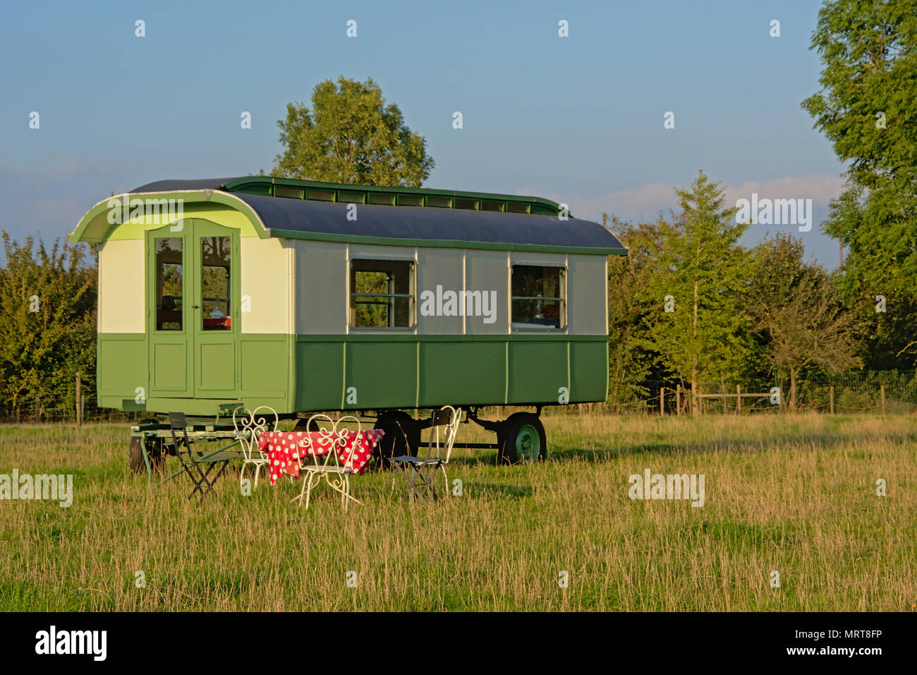 Verde romantica di legno verniciato caravan vintage con tavolo e sedie in natura nelle Fiandre Foto Stock