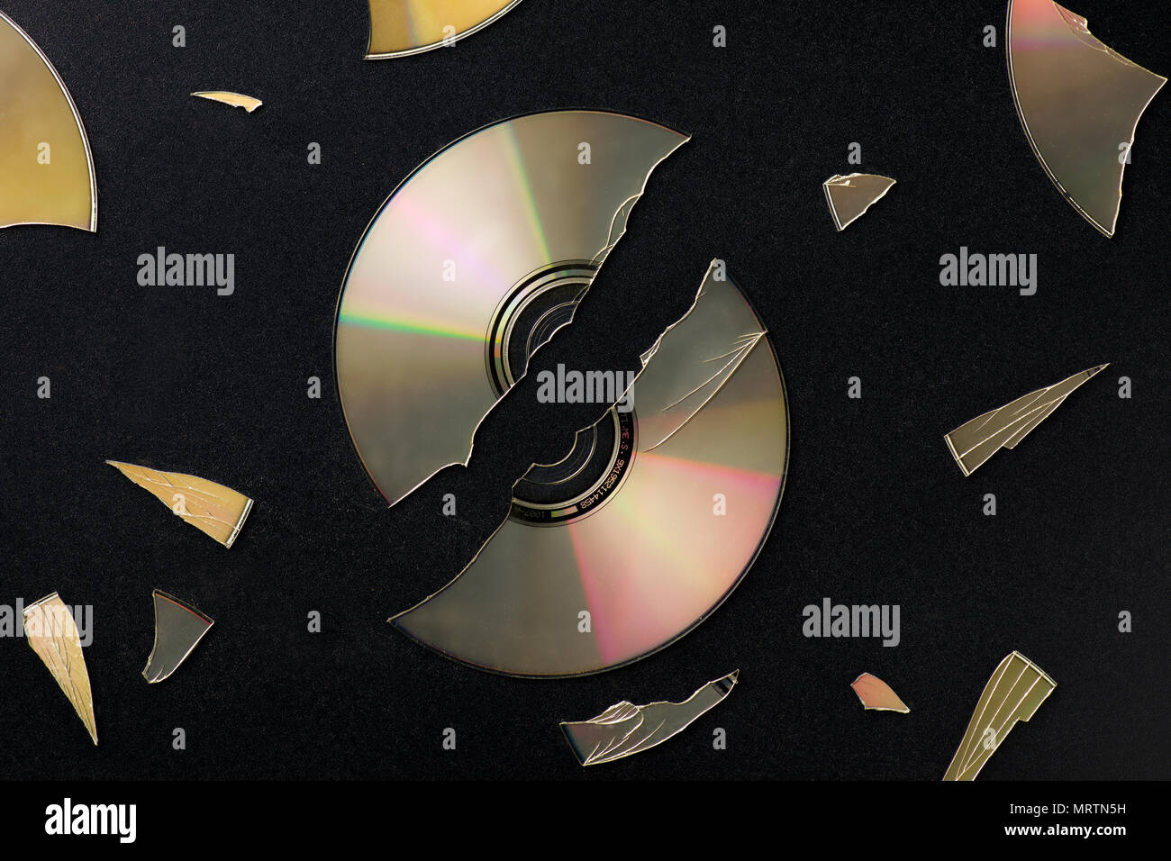 Rotture di Compact Disc con pezzi Scattared sulla superficie nera Foto Stock