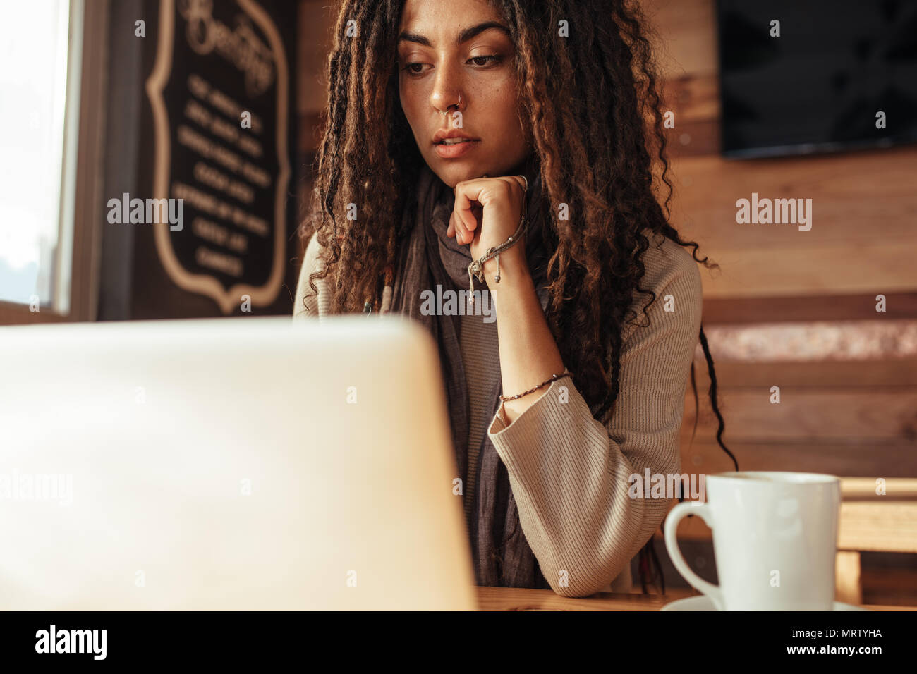 Primo piano di una donna seduta in un ristorante di lavoro del tavolo sul laptop. Libero professionista in seduta cafe con un caffè lavorando sul computer portatile. Foto Stock