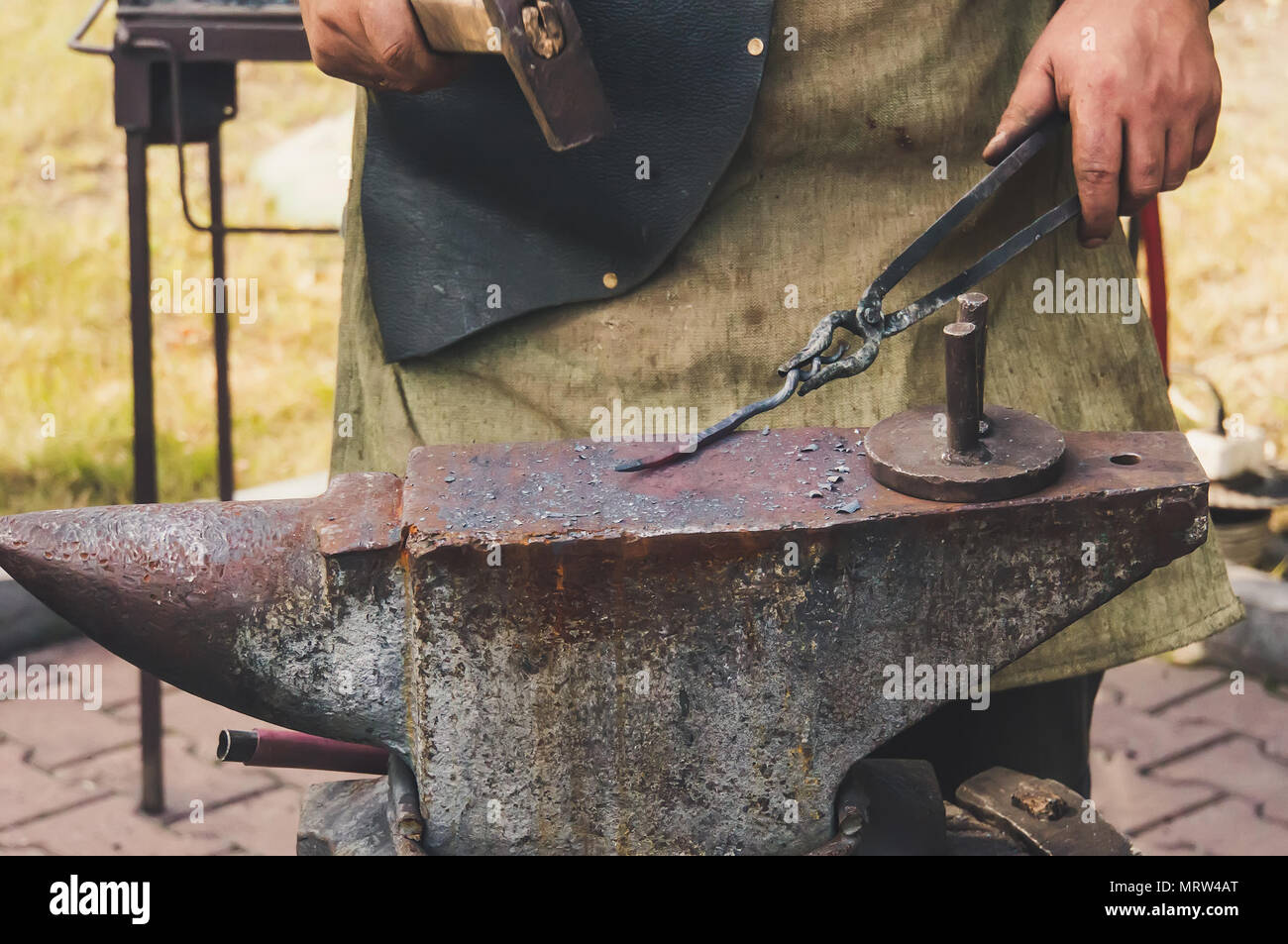 Dettaglio colpo di martello a caldo forgiatura del ferro all'incudine. Martello di forgiatura di strutture metalliche all'aria aperta in una ghisa incudine Foto Stock