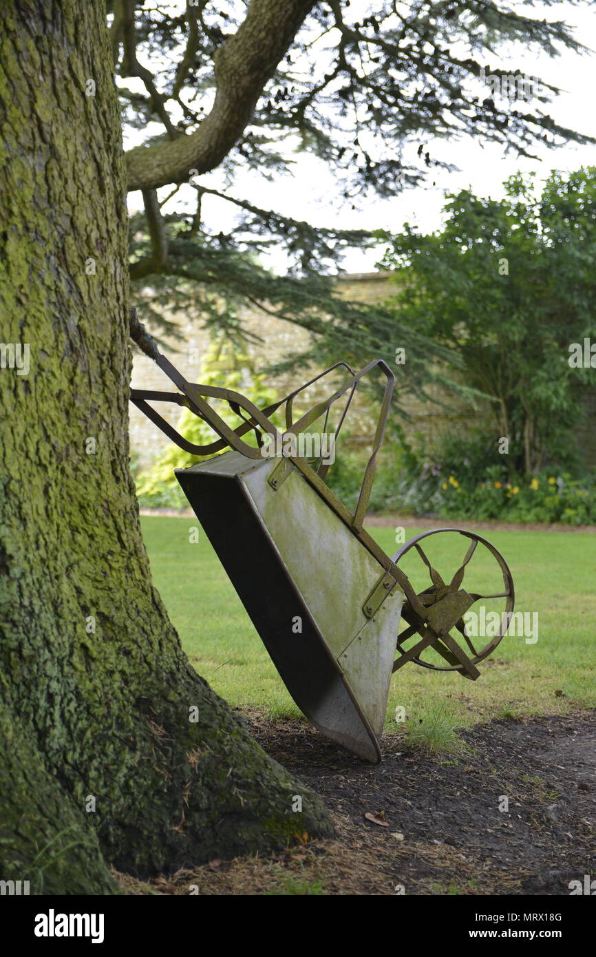 Antique Victorian carriola appoggiata contro un CedarTree, Canons Ashby, Northamptonshire Foto Stock