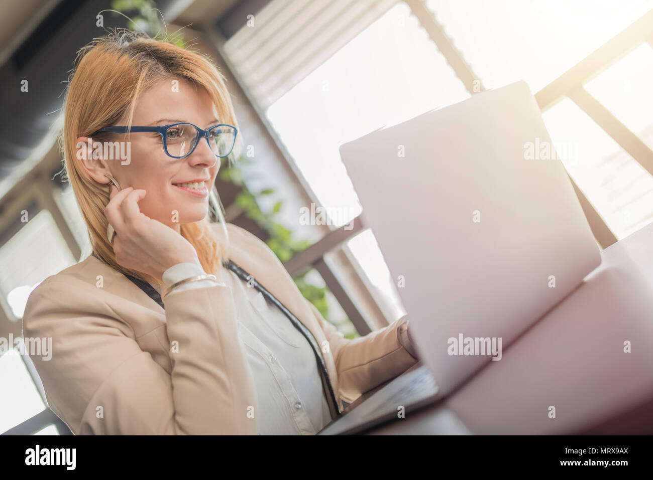 Business donna sta lavorando sul computer portatile in una caffetteria, ristorante. Affascinante ragazza felice è utilizzando il computer portatile per preparare per il lavoro. Bella ragazza con gla Foto Stock